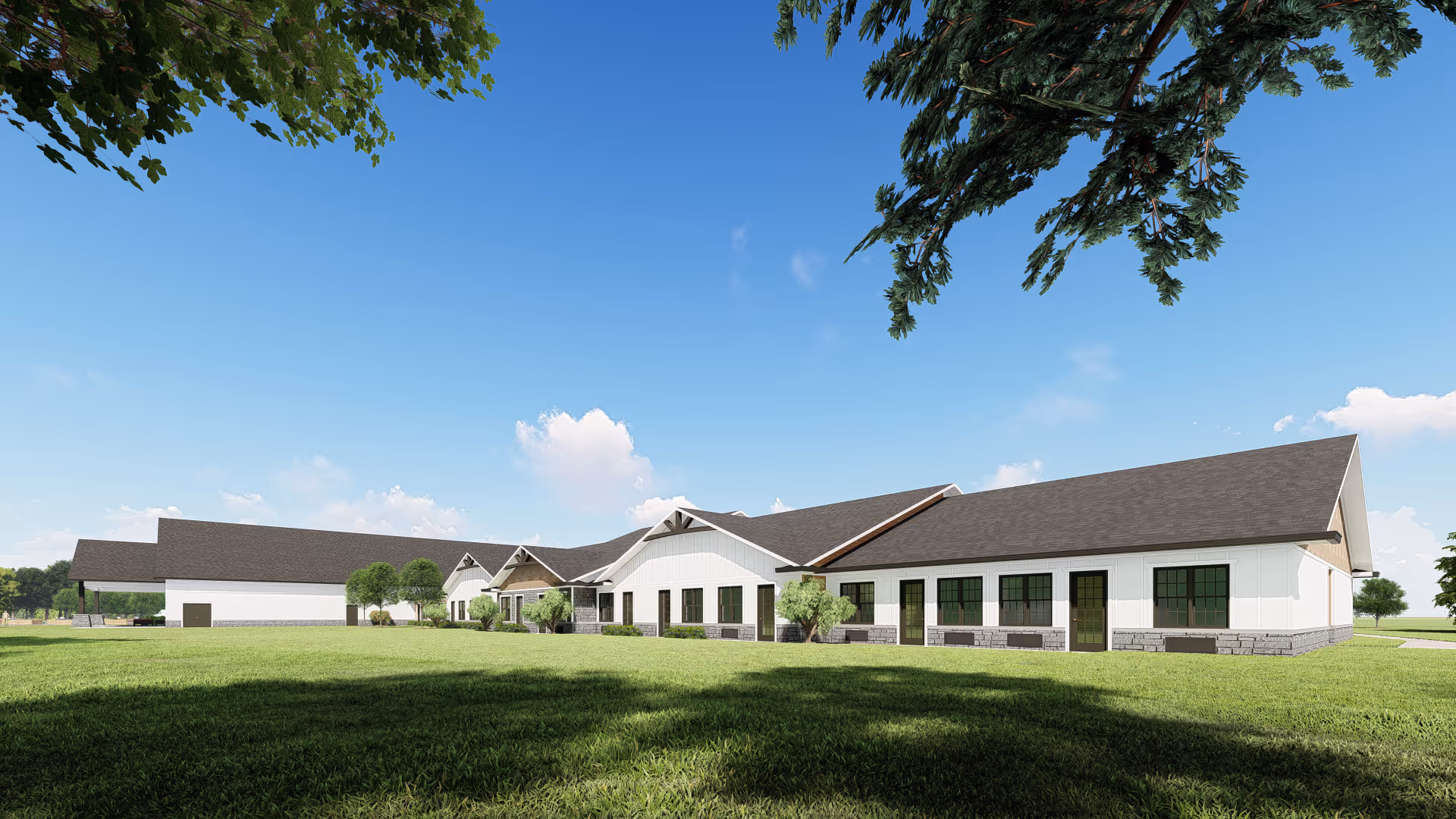 Exterior view of a single-story assisted living facility building with white walls, dark roof, and multiple windows, surrounded by green grass and trees under a clear blue sky.