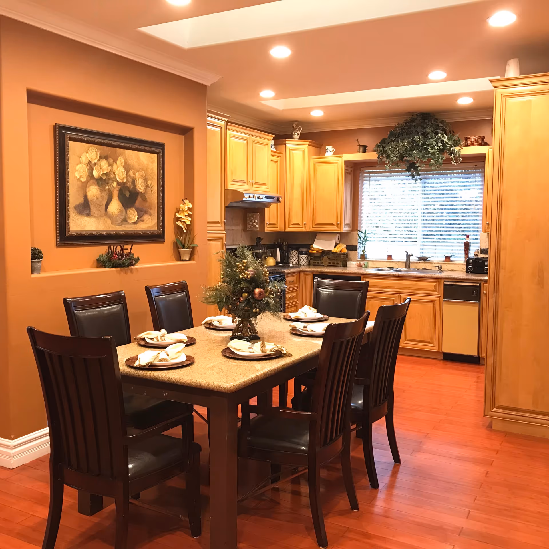 Warm dining area with a large table set for six, open kitchen in background.
