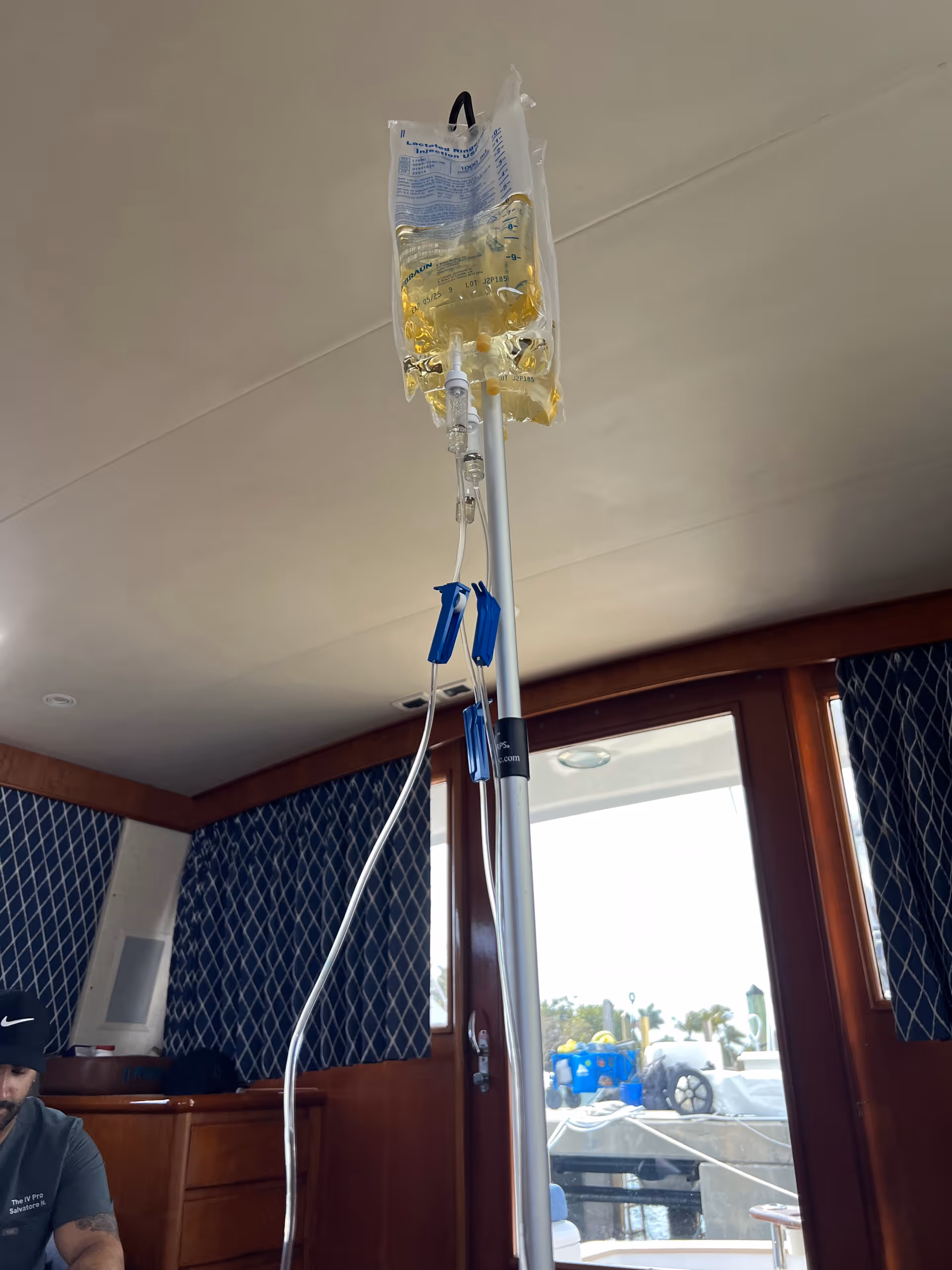 IV drip bag on a stand inside a boat cabin with blue patterned walls
