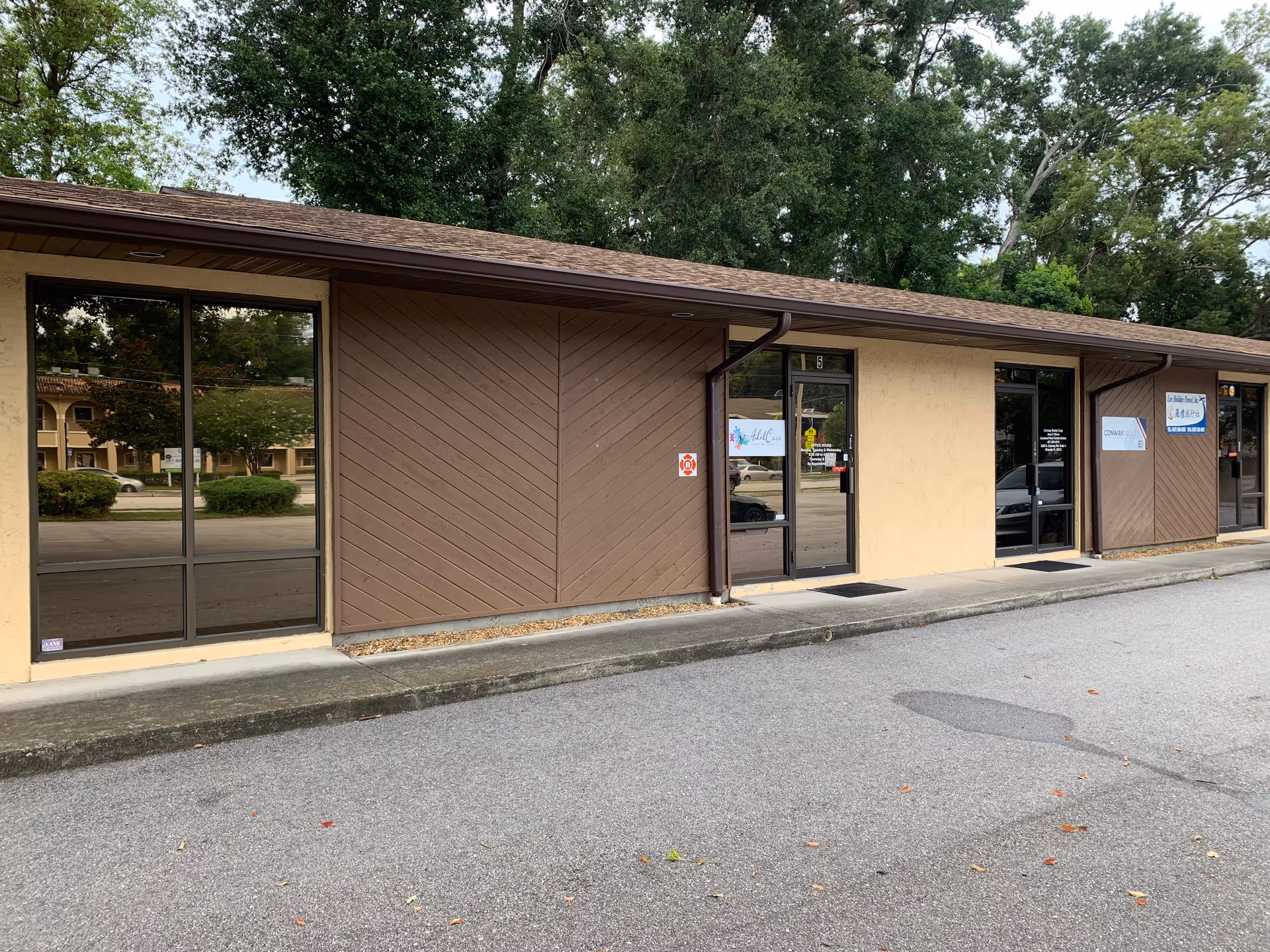 Exterior view of AdelCare II facility storefront with brown siding and large glass doors.