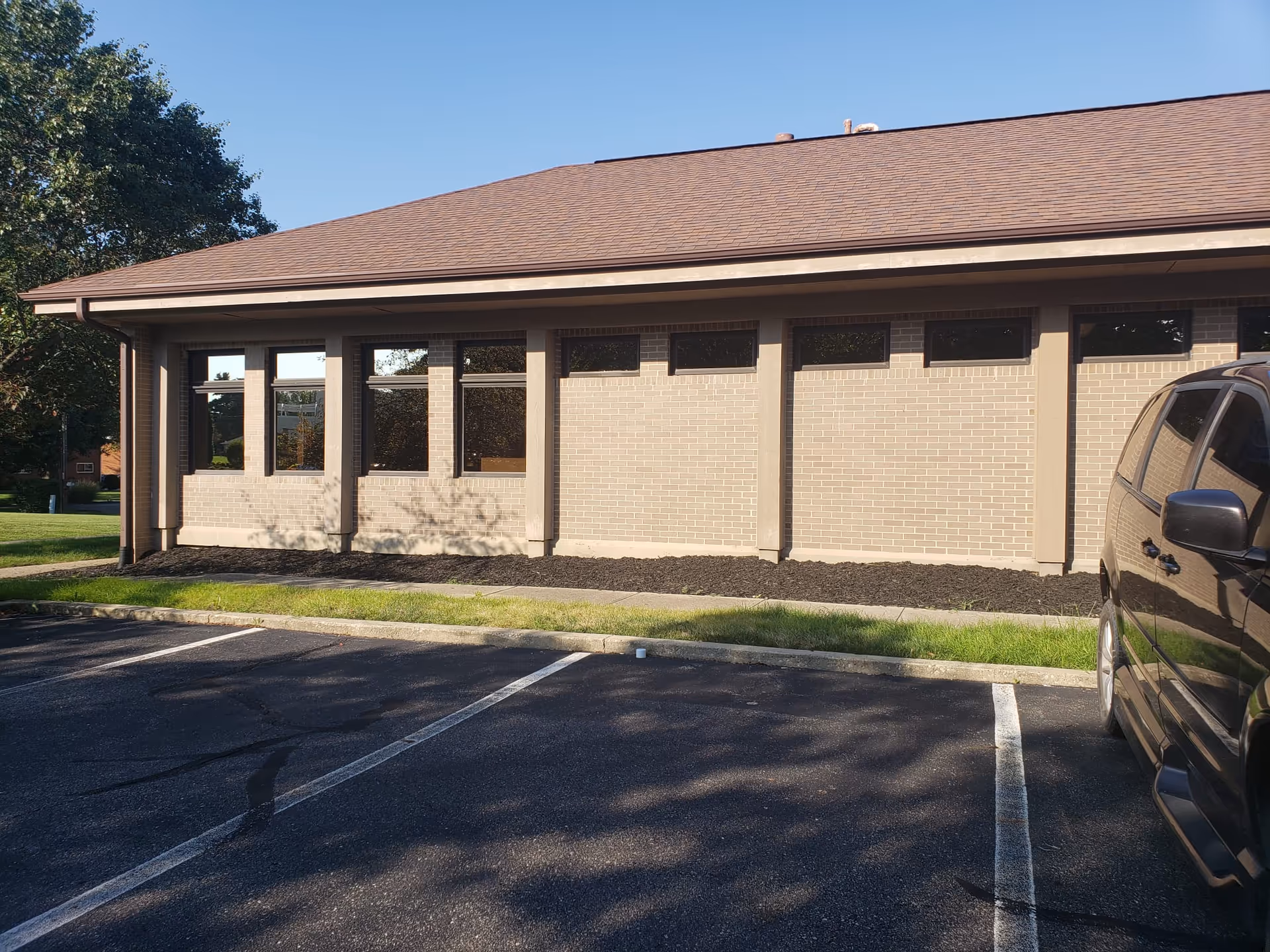 Exterior of a single-story brick nursing facility with parking in front.