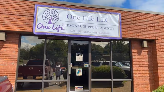 Brick storefront of One Life LLC Personal Support Agency with glass doors and an open sign.