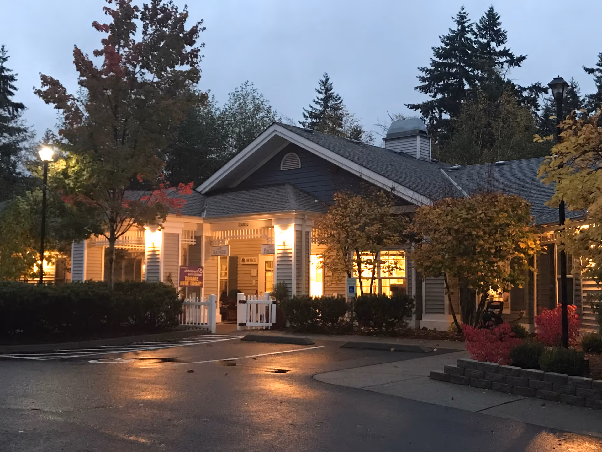 Exterior view of Cottages at Mill Creek showing lit entrance and autumn landscaping.