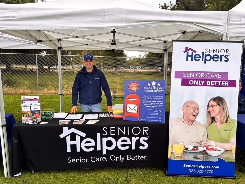 Outdoor Senior Helpers booth under a white tent promoting senior care services.