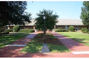 Exterior view of Warner Robins Rehabilitation Center with a brick walkway and green lawn.