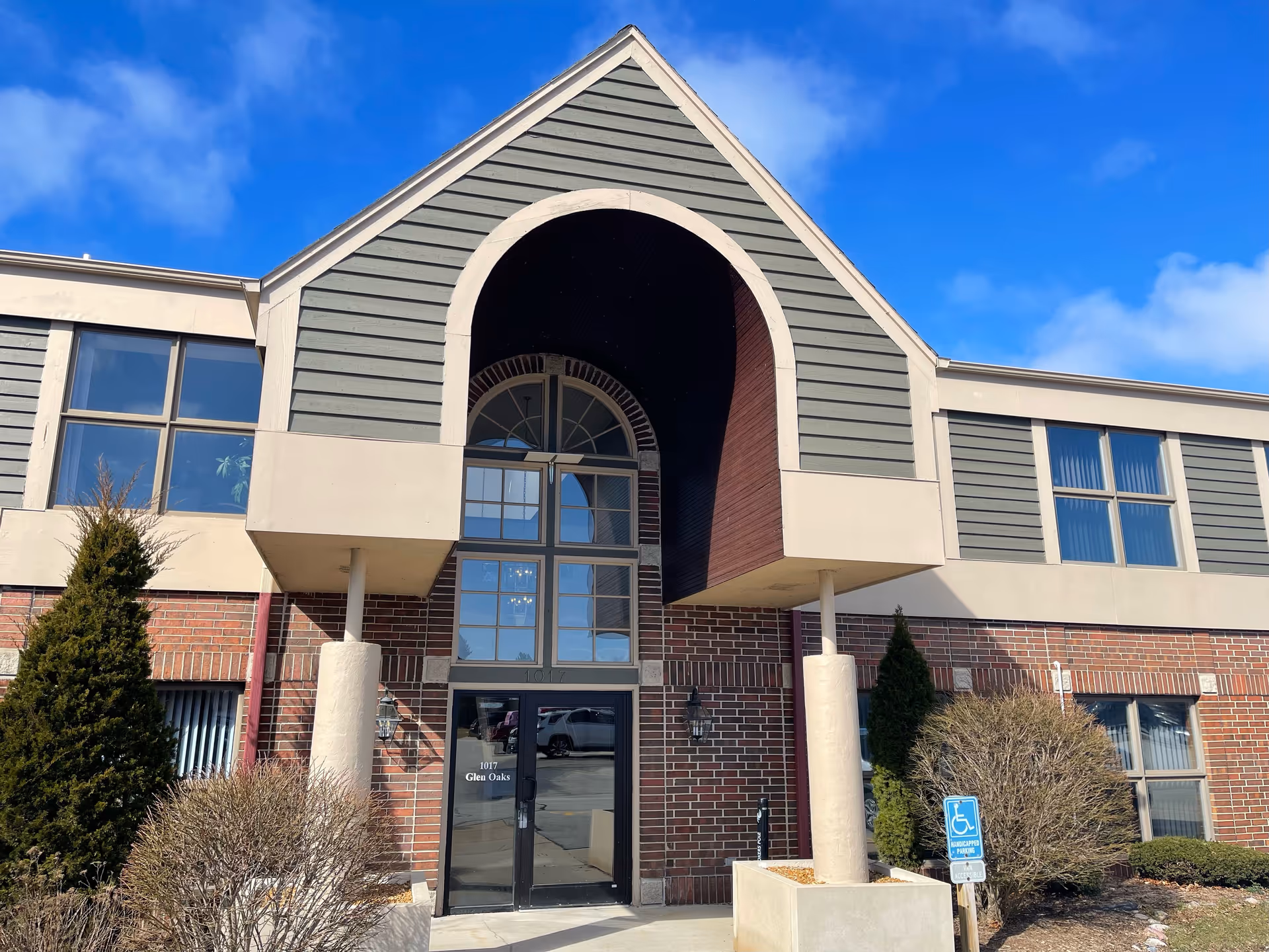Front exterior of a senior living facility with arched entry and brick façade.