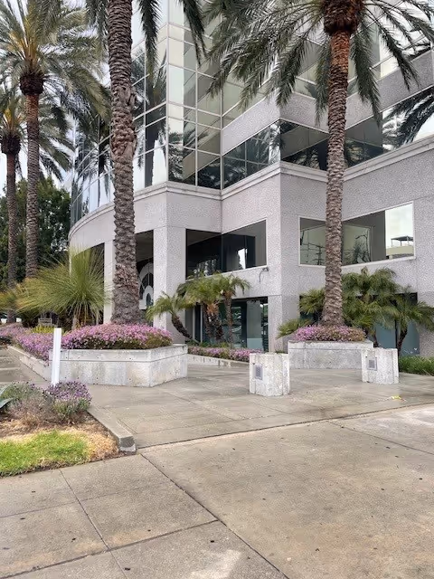 Modern gray glass building exterior of a senior living facility with palm trees at the entrance.