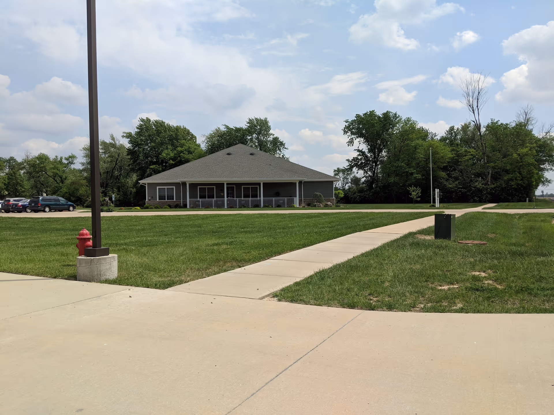 Single-story building with a walkway, lamppost, and expansive grassy grounds.