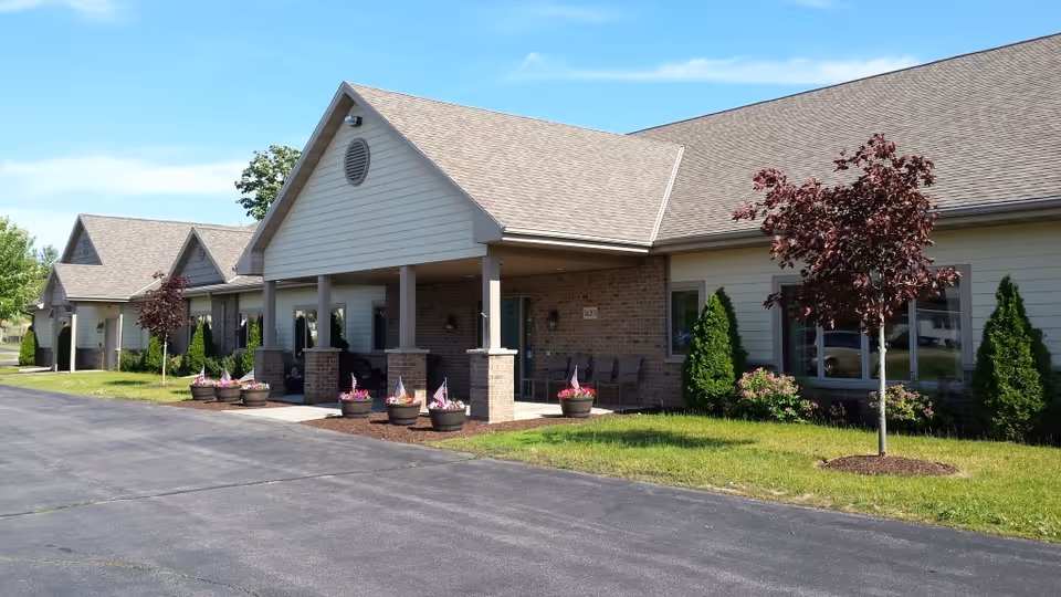 Single-story senior living facility with a covered front entrance, brick columns, and landscaped surroundings.