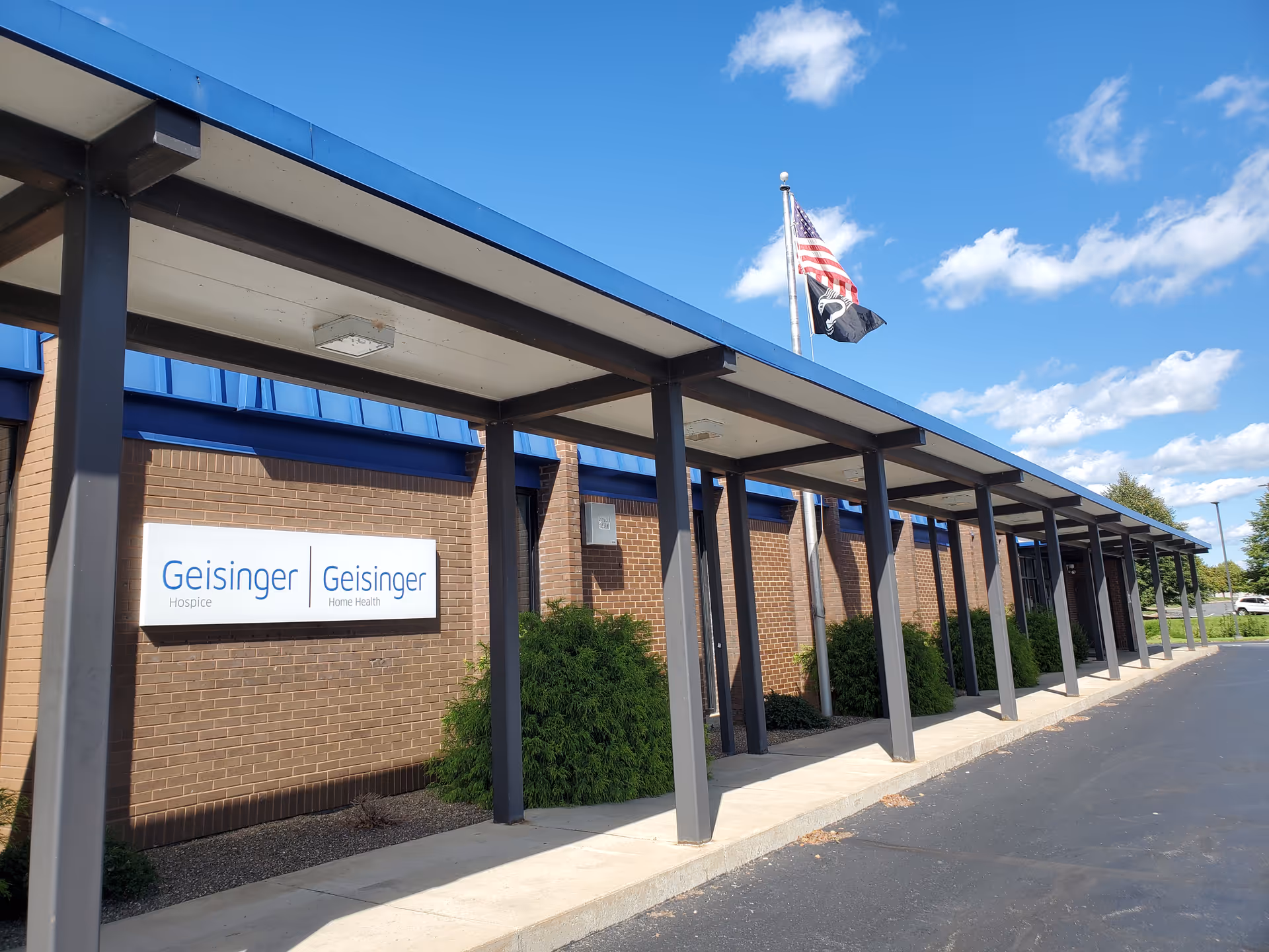 Exterior view of Geisinger Hospice building with blue canopy and flag.