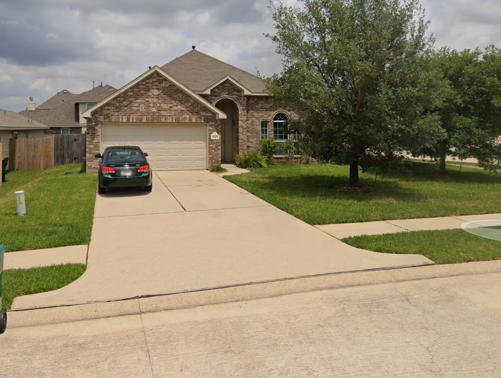 Front view of a brick house with driveway and green lawn.