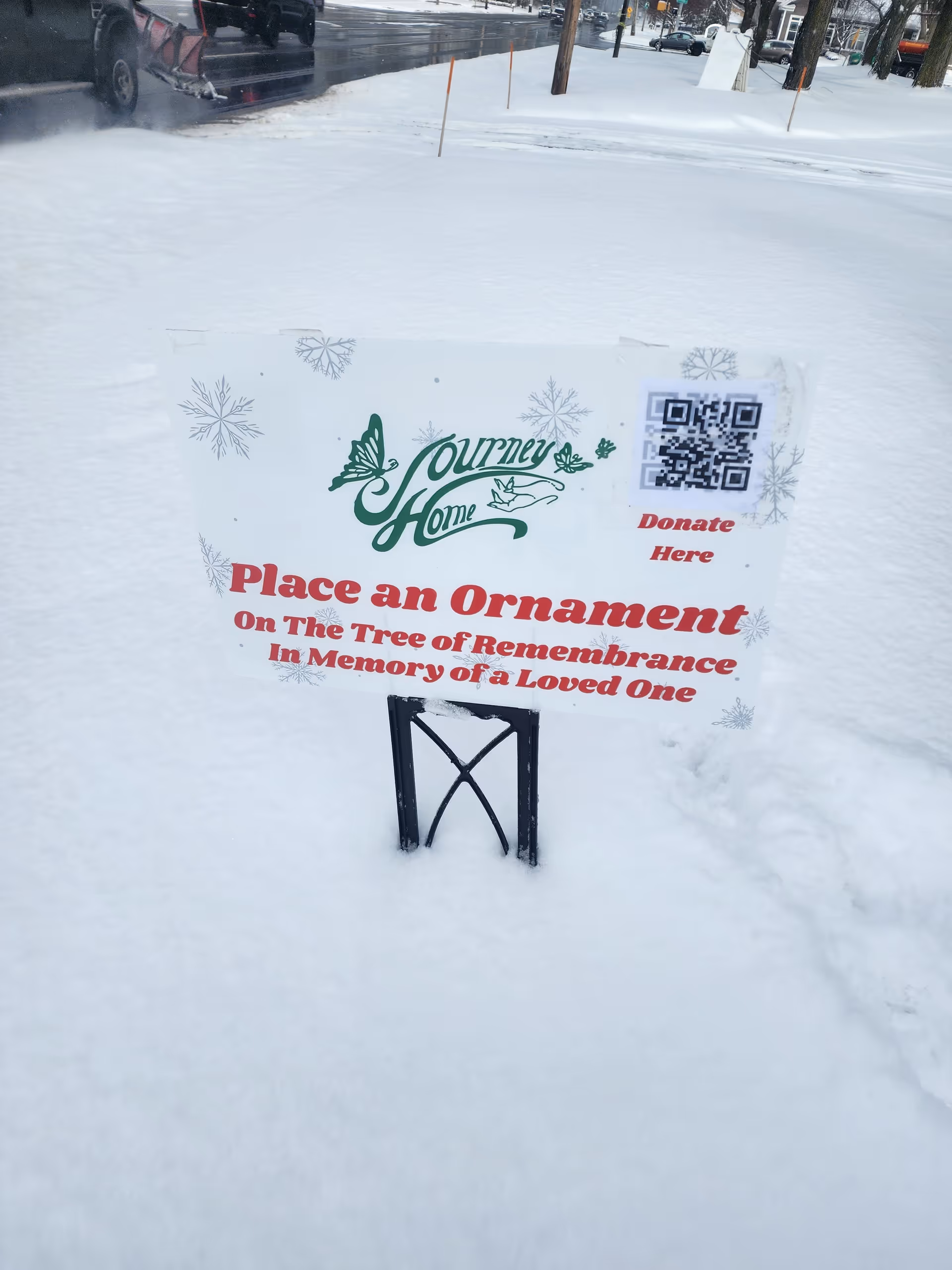Outdoor snowy scene with Journey Home sign promoting ornament remembrance donation.