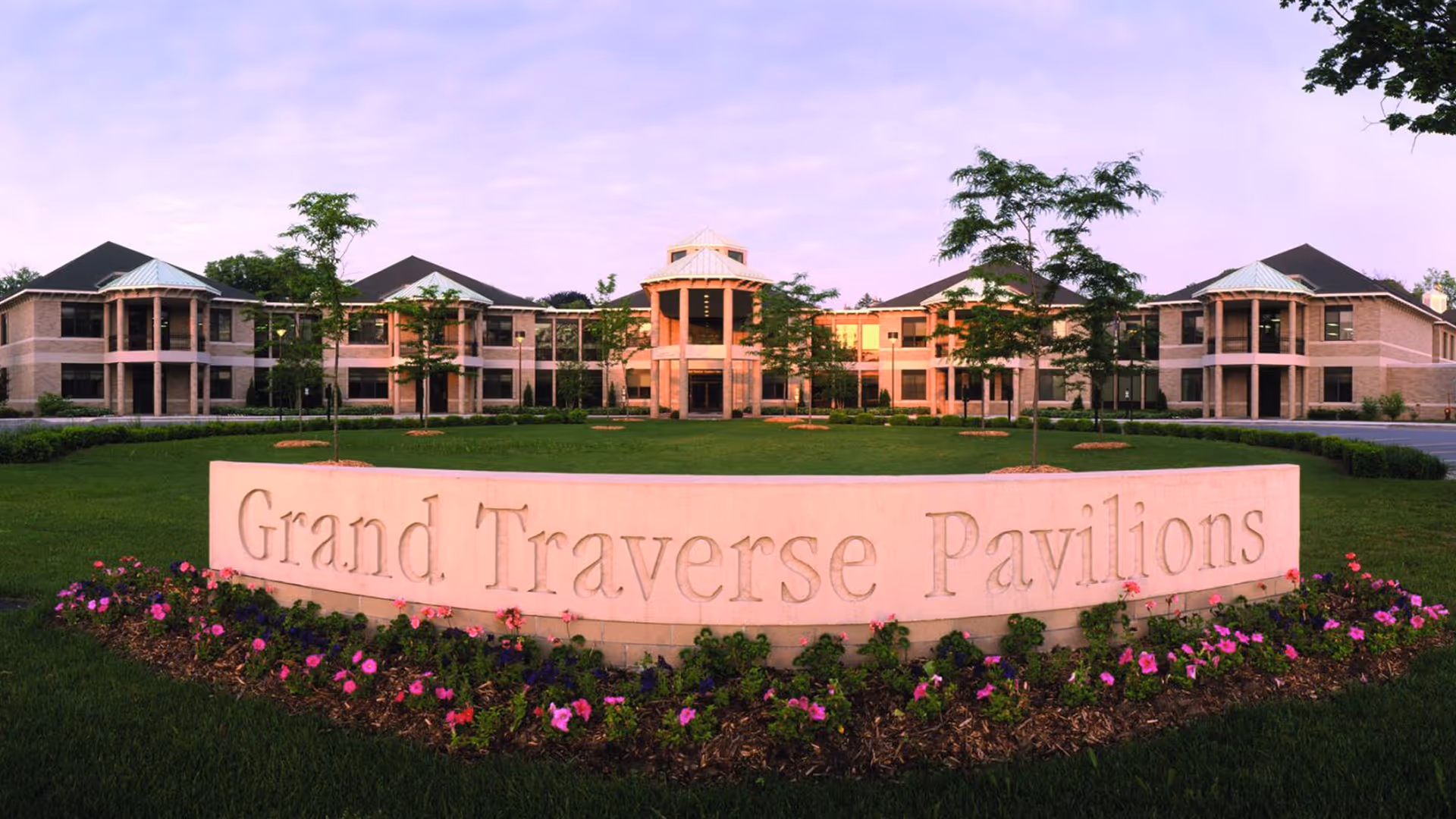 Exterior view of Grand Traverse Pavilions with a curved sign and manicured lawn.
