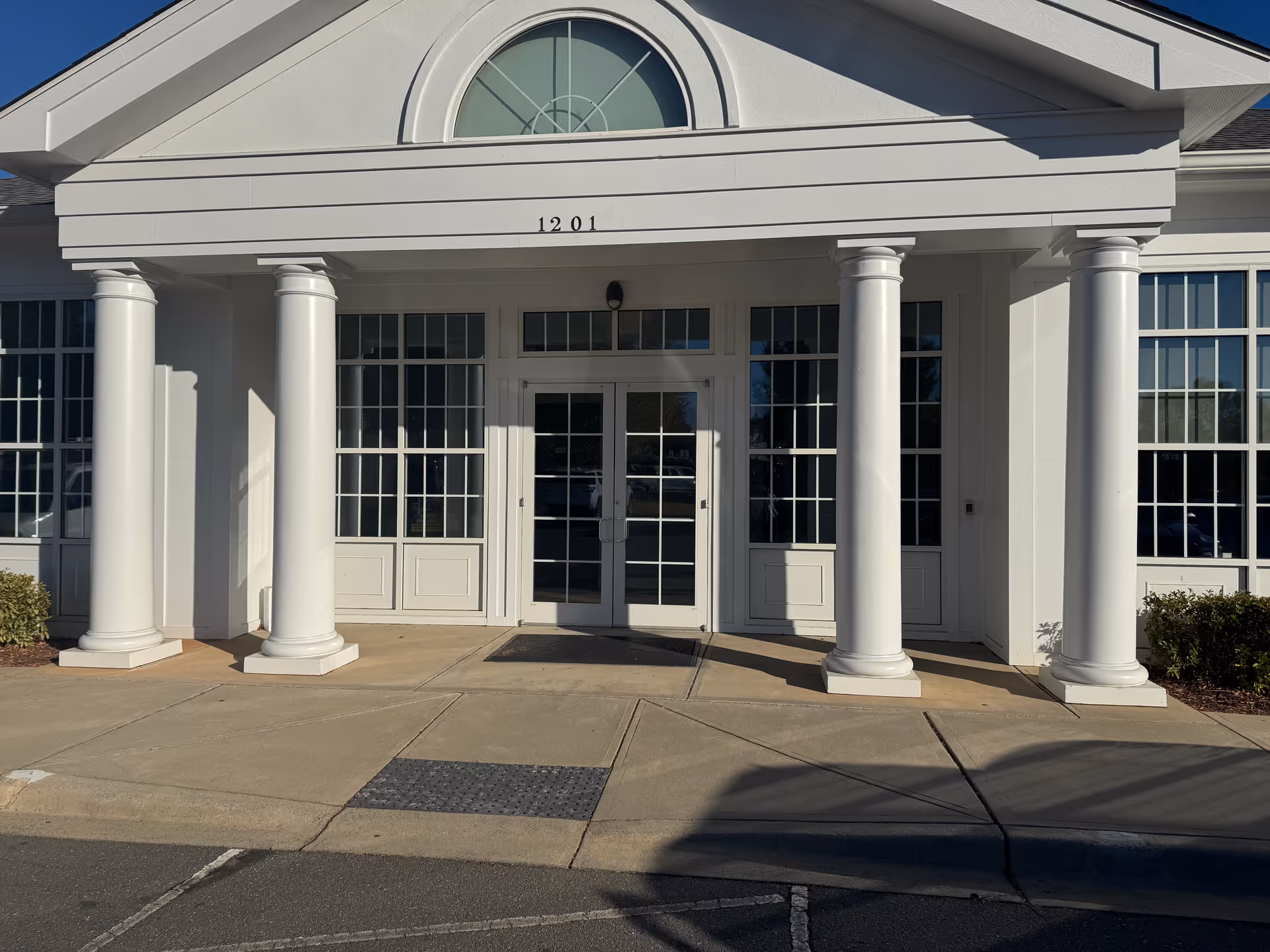White building entrance with tall columns and double glass doors at 1201