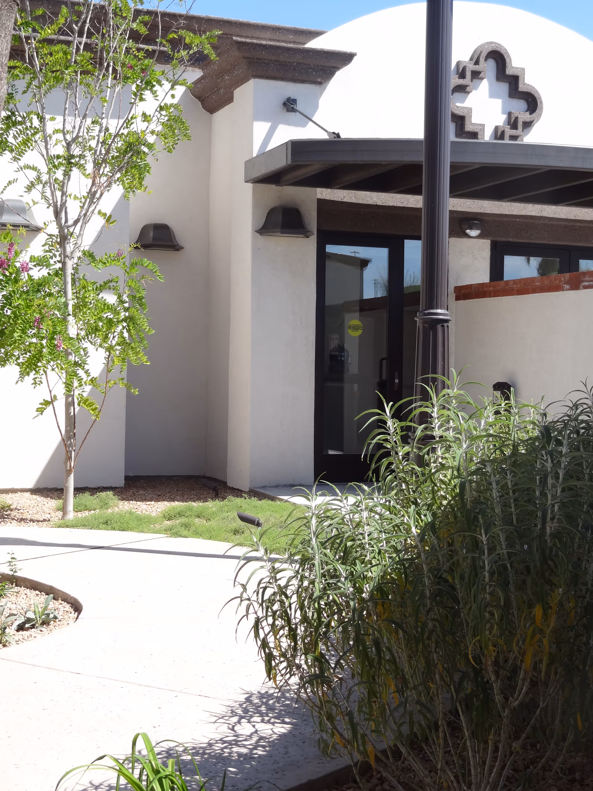 Exterior entrance of a senior facility with glass doors and landscaping.