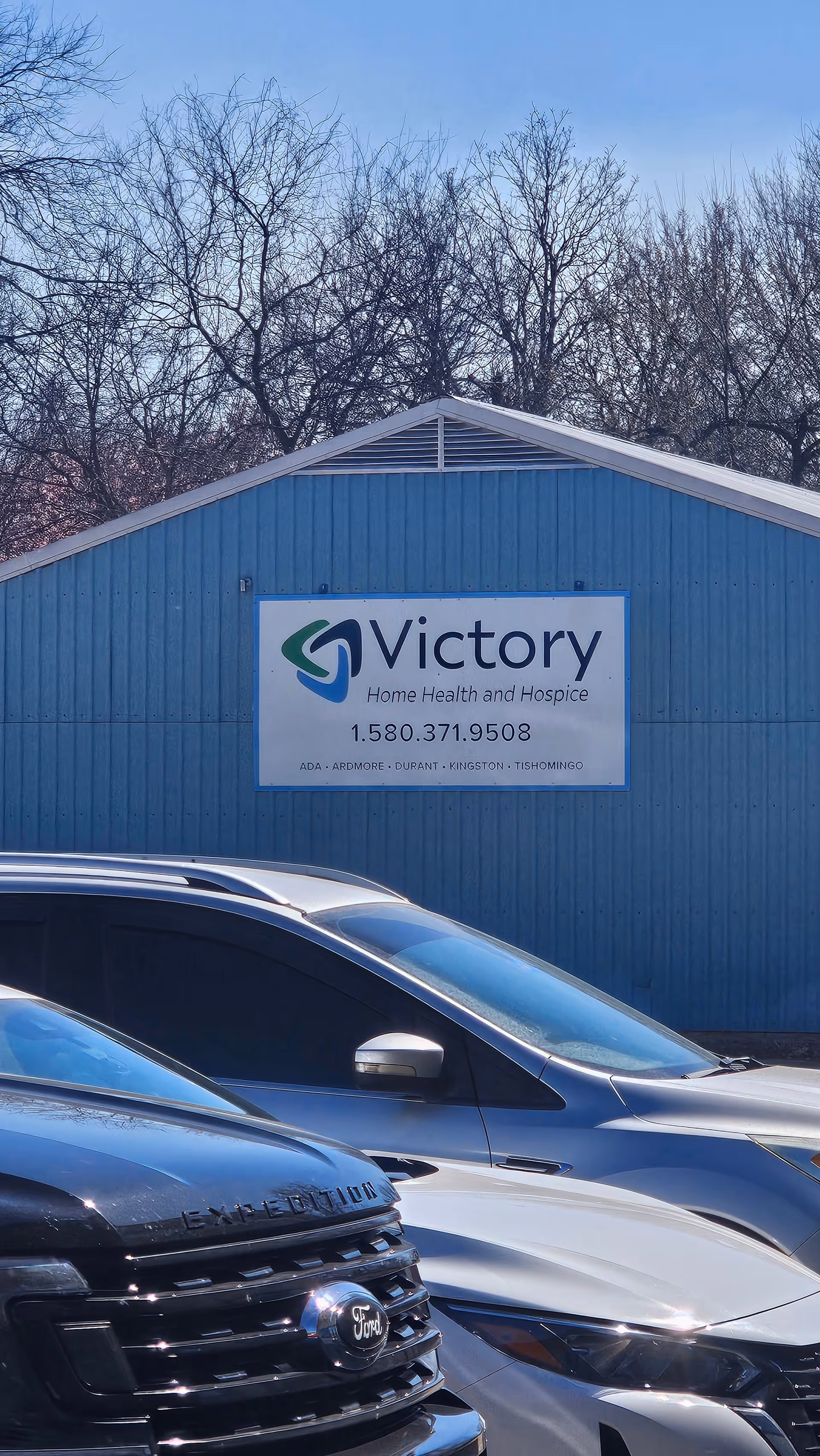 Blue building exterior with Victory Home Health and Hospice sign and parked cars.