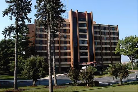 Front exterior view of Conestoga View, a multi-story brick senior living building with trees.