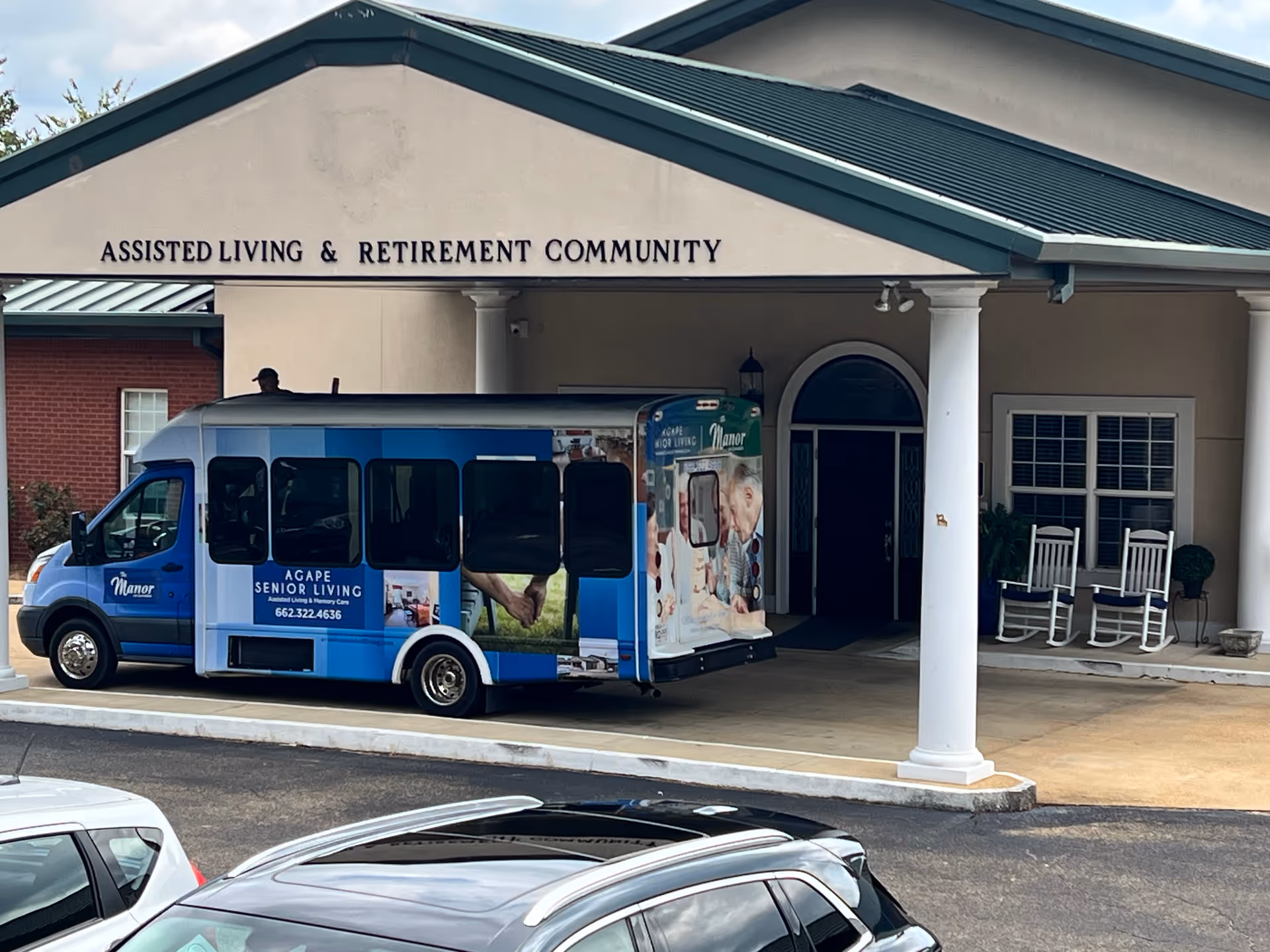 Assisted living and retirement community entrance with a shuttle bus parked out front.