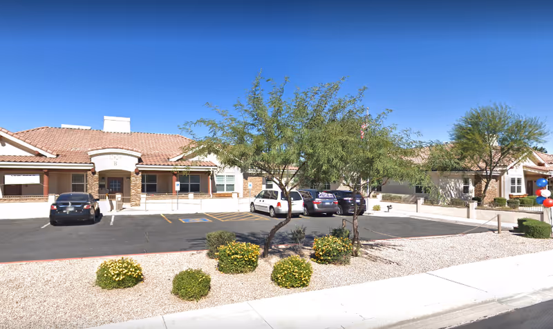Front exterior view of Avista Sun City West Memory Care with parking lot and desert landscaping.