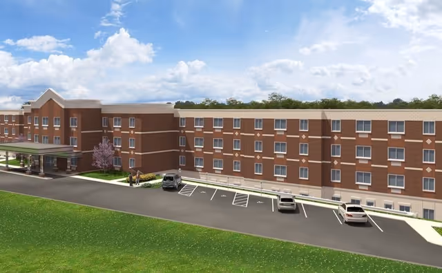 A brick senior living facility with multiple windows, an entry canopy, and a parking lot.