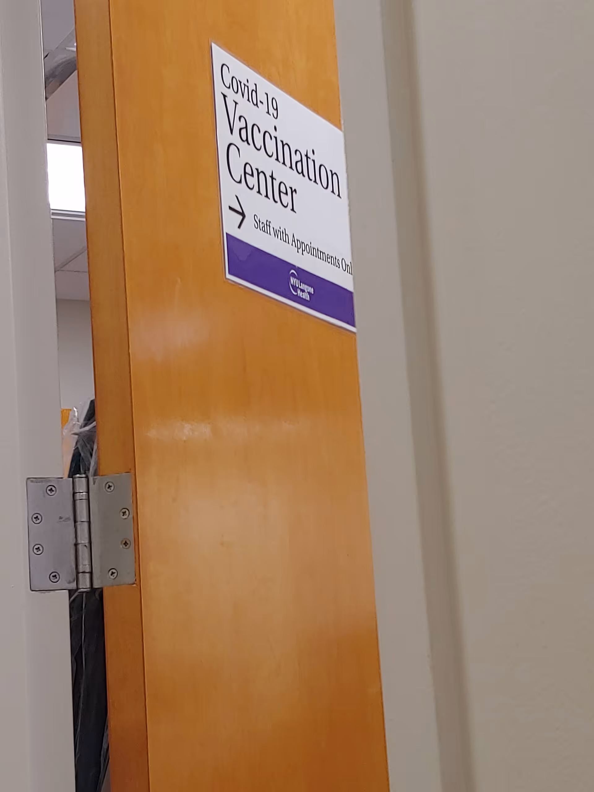 Interior wooden door with a Covid-19 Vaccination Center sign posted.