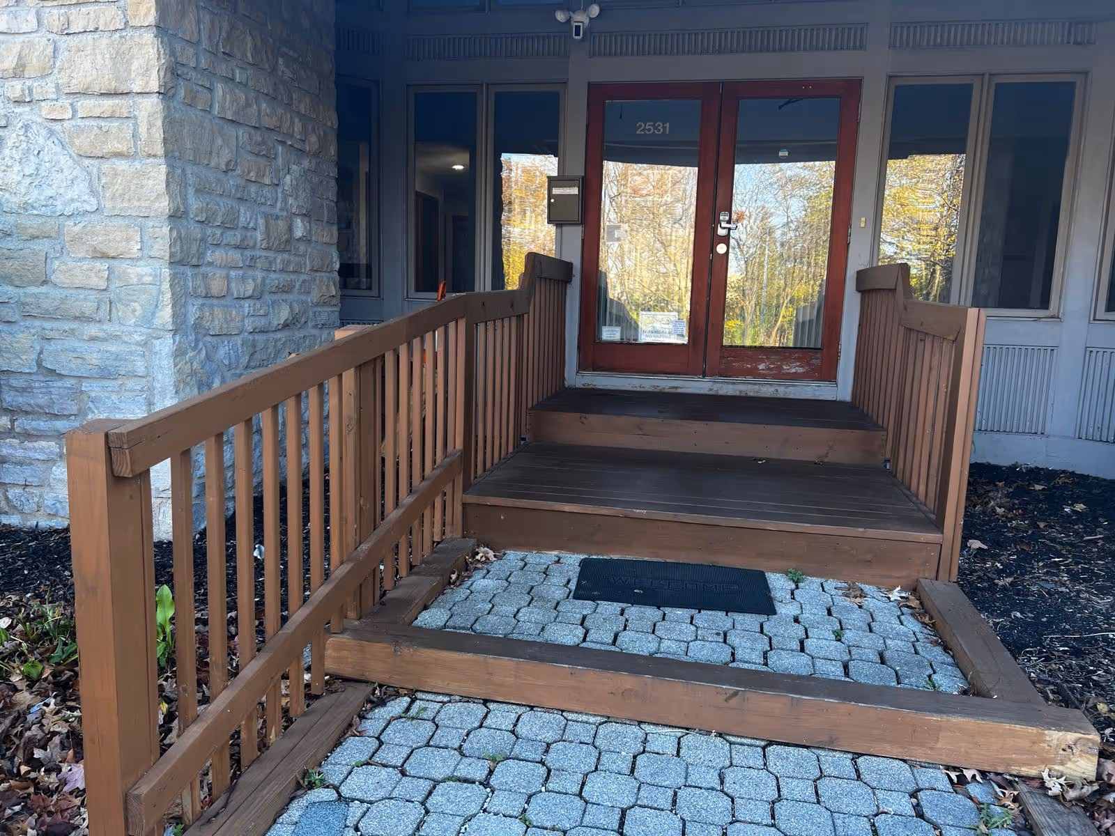 Front entrance of a building with a wooden ramp and glass doors.