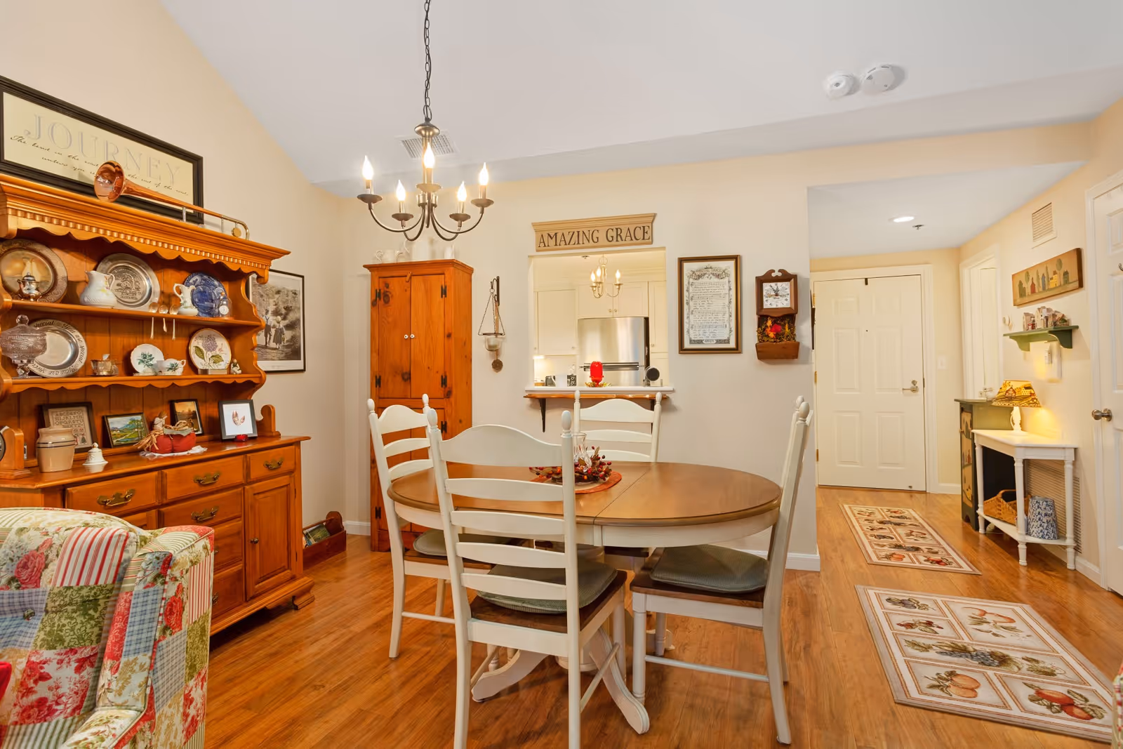 Cozy dining room with round table, chairs, cabinet, and kitchen doorway in background.