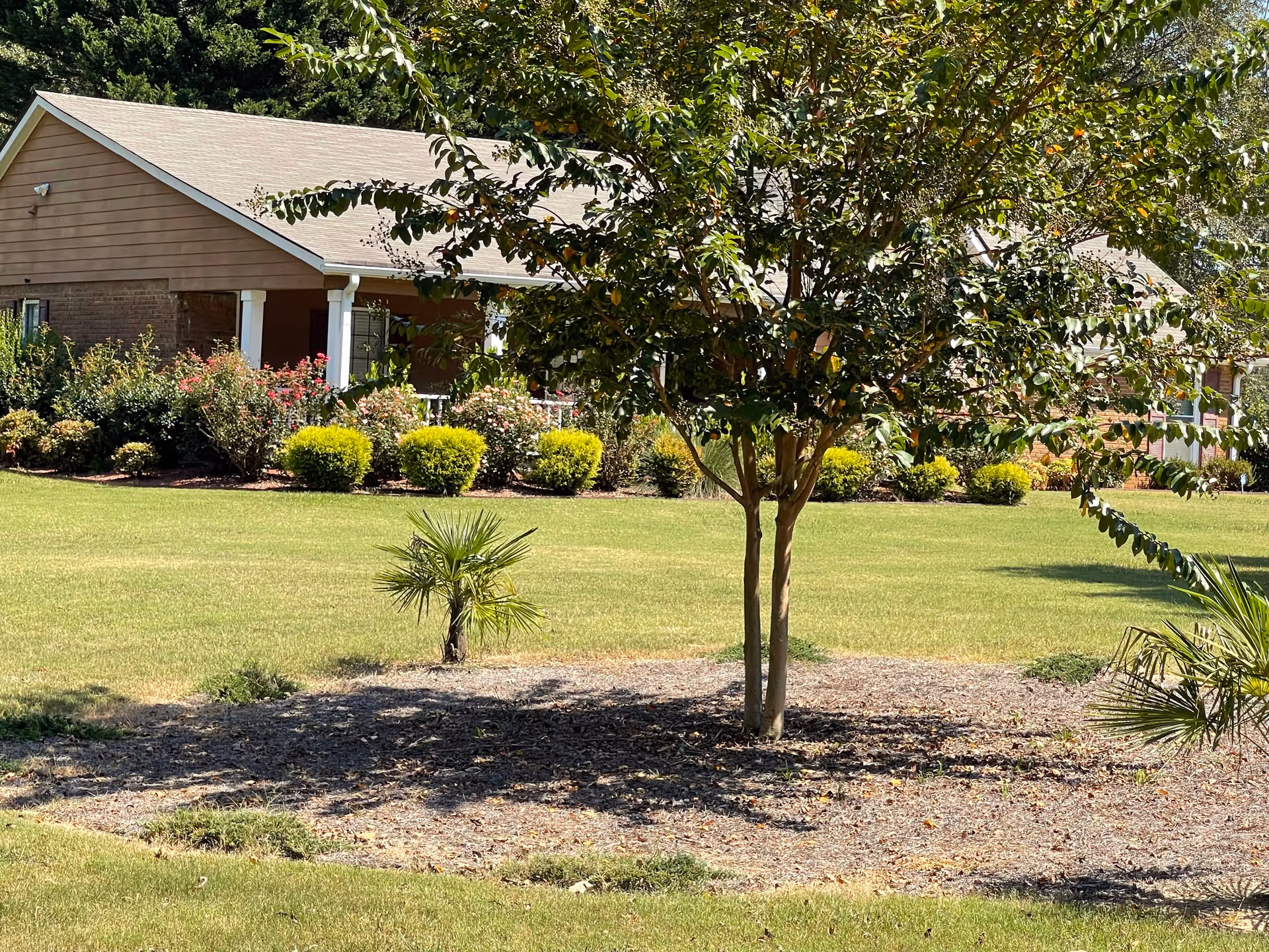 Front view of Estella House senior living facility with lawn, shrubs, and trees.