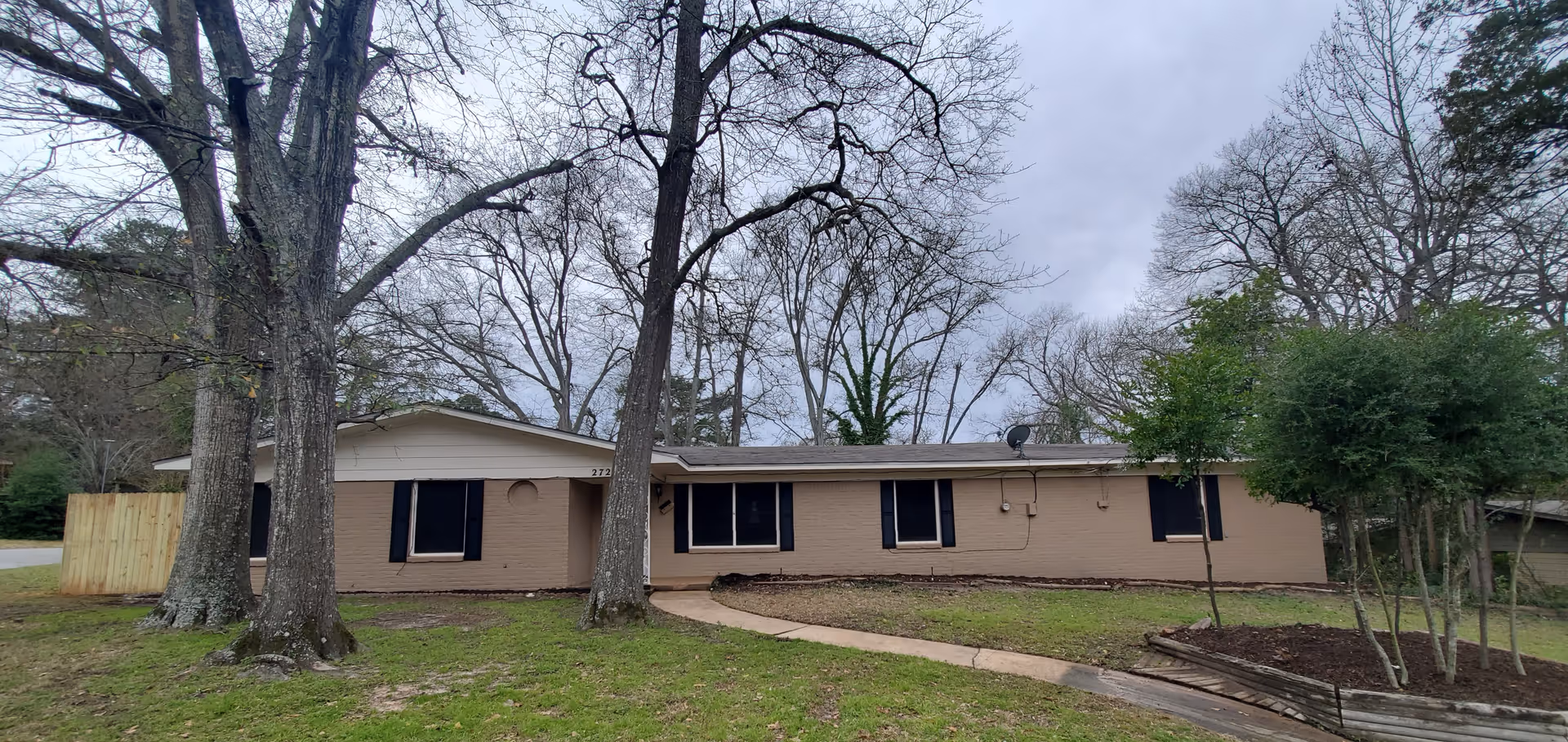 The Rose Residential Care Home, LLC exterior: single-story beige building with trees and walkway.