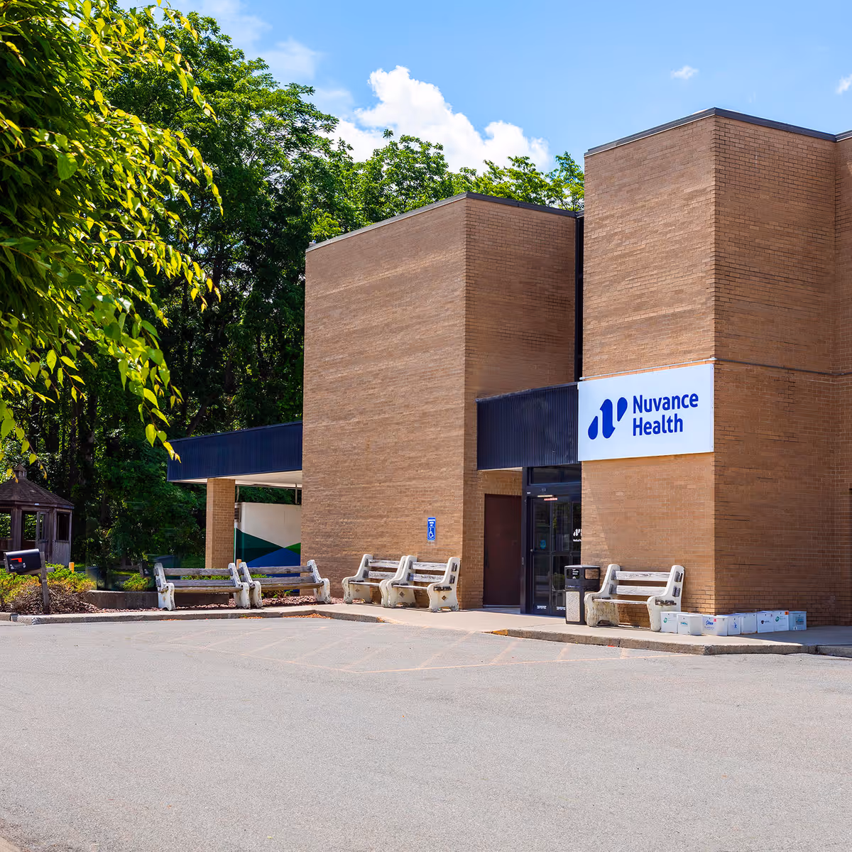 Exterior view of a brick medical building with a Nuvance Health sign and benches.
