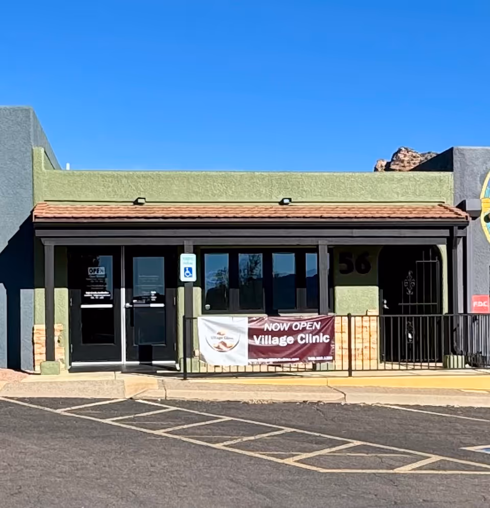 Front view of a green storefront with glass doors and a 'Village Clinic' banner.