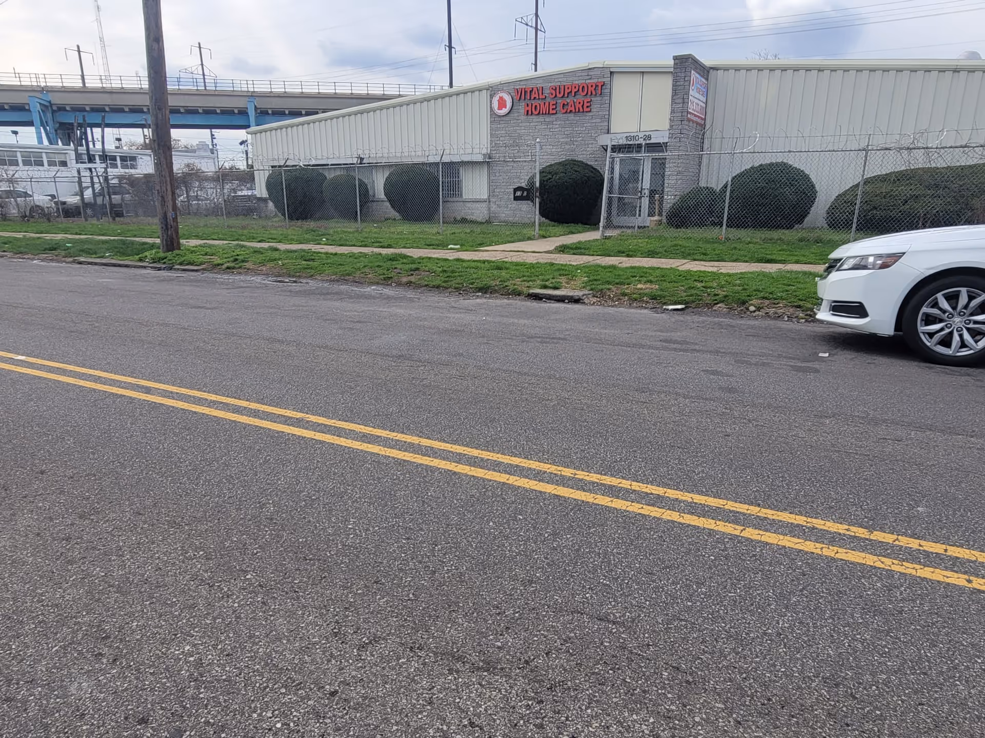 Exterior view of Vital Support Home Care building with fence and parked car