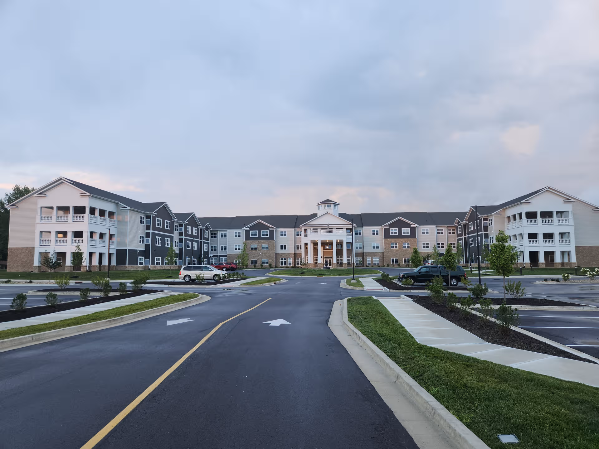 Wide view of Avalon Senior Living's modern multi-wing exterior with a central entrance and parking.