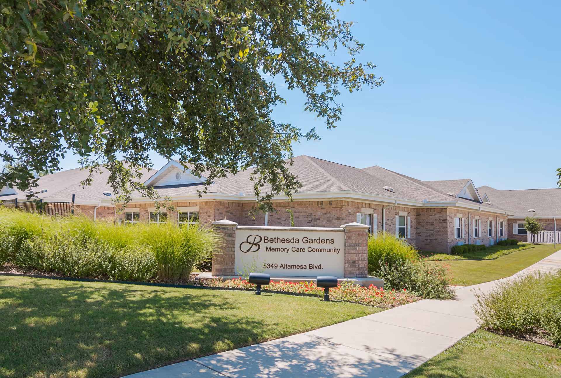 A brick senior living facility exterior with Bethesda Gardens sign and manicured landscaping.