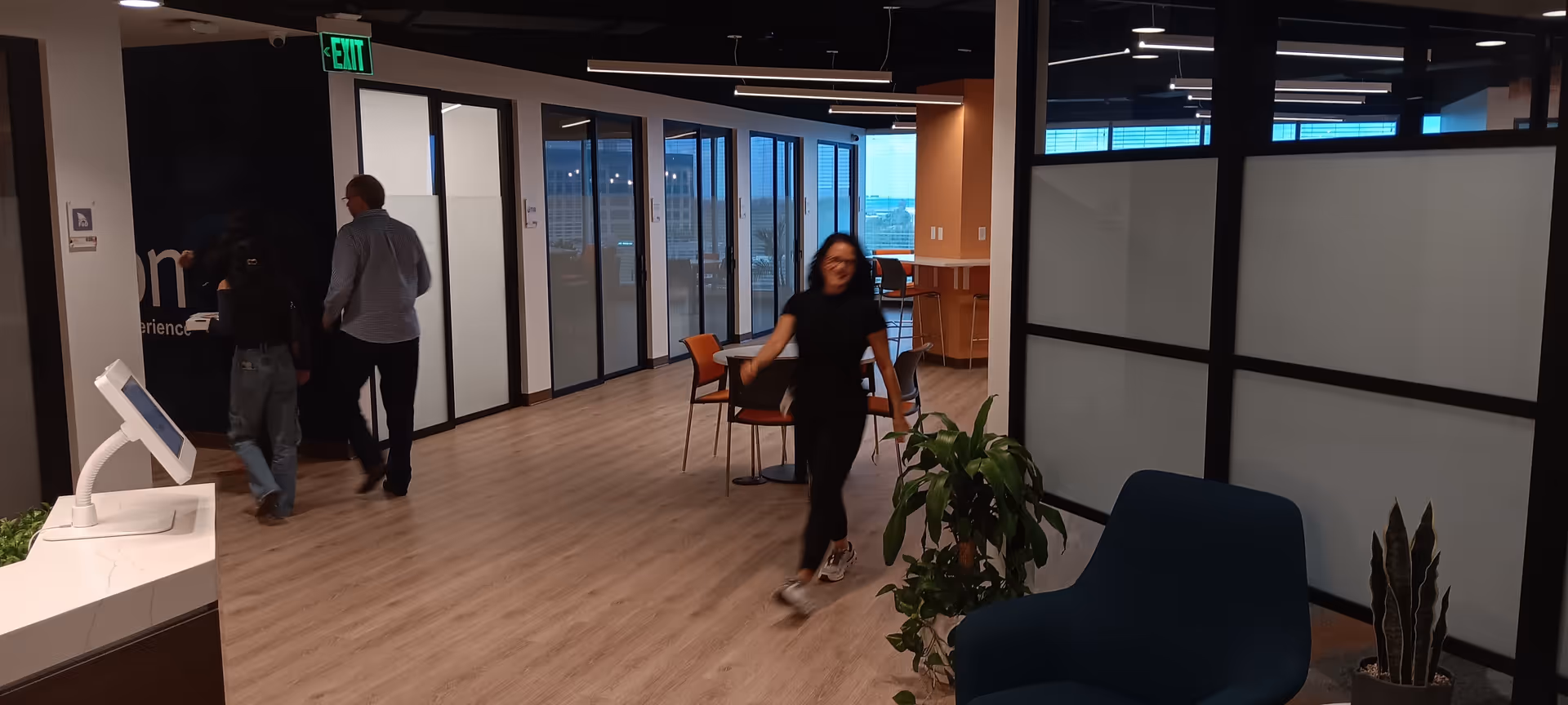 Bright modern senior living lobby with glass offices, plants, and people walking through.