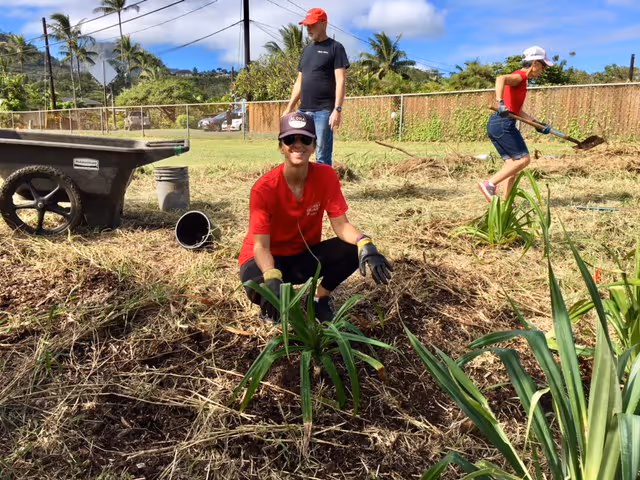 Three caregivers gardening outdoors near a wheelbarrow at BAYADA Kauai Home Care.