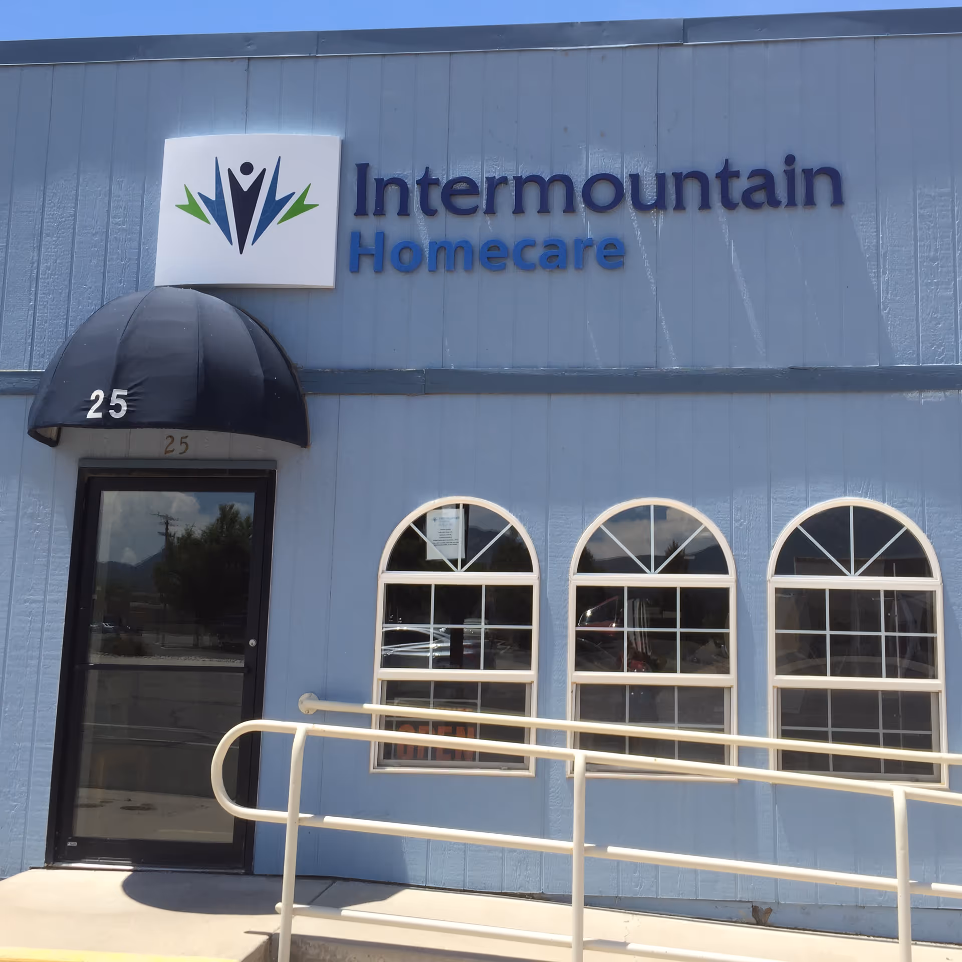 Blue building exterior with Intermountain Homecare sign, arched windows, and a black entrance canopy.