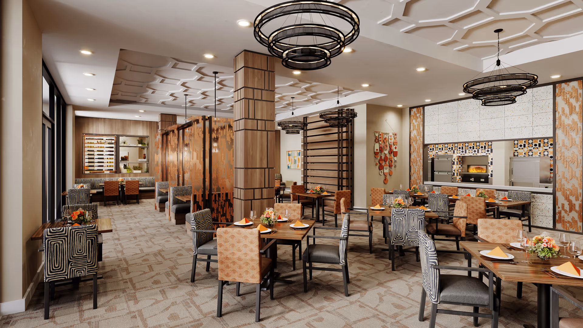 A spacious and elegant dining room with multiple tables set with plates, napkins, and floral centerpieces. The room features patterned carpet, modern light fixtures, decorative wooden columns, and a wall with built-in ovens. There are a variety of upholstered chairs in different patterns and colors, and large windows along one side of the room.