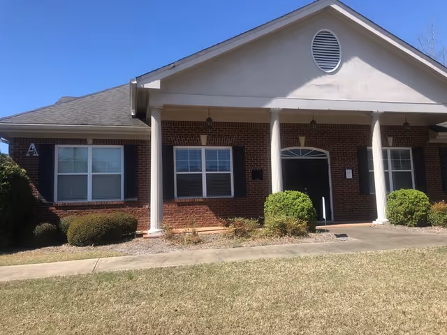 Brick senior living facility exterior with columns and a front entrance.