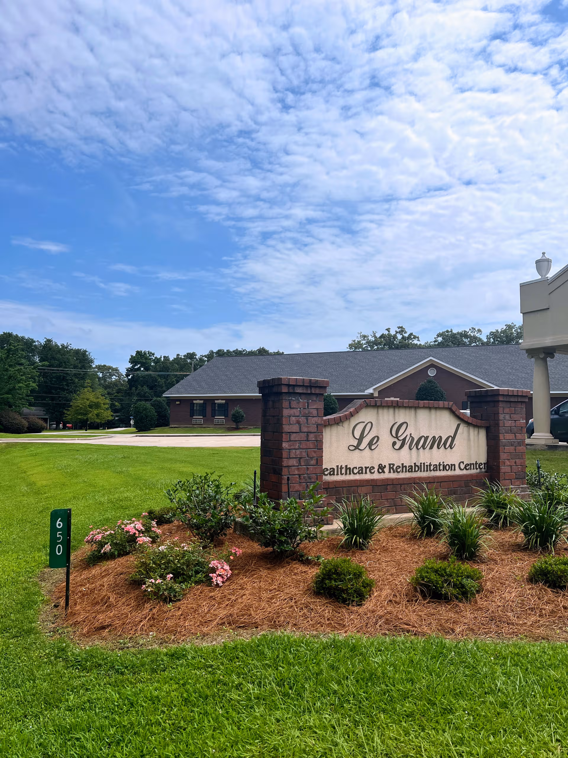 Front view of Le Grand Health Care & Rehabilitation Center sign with landscaped lawn.