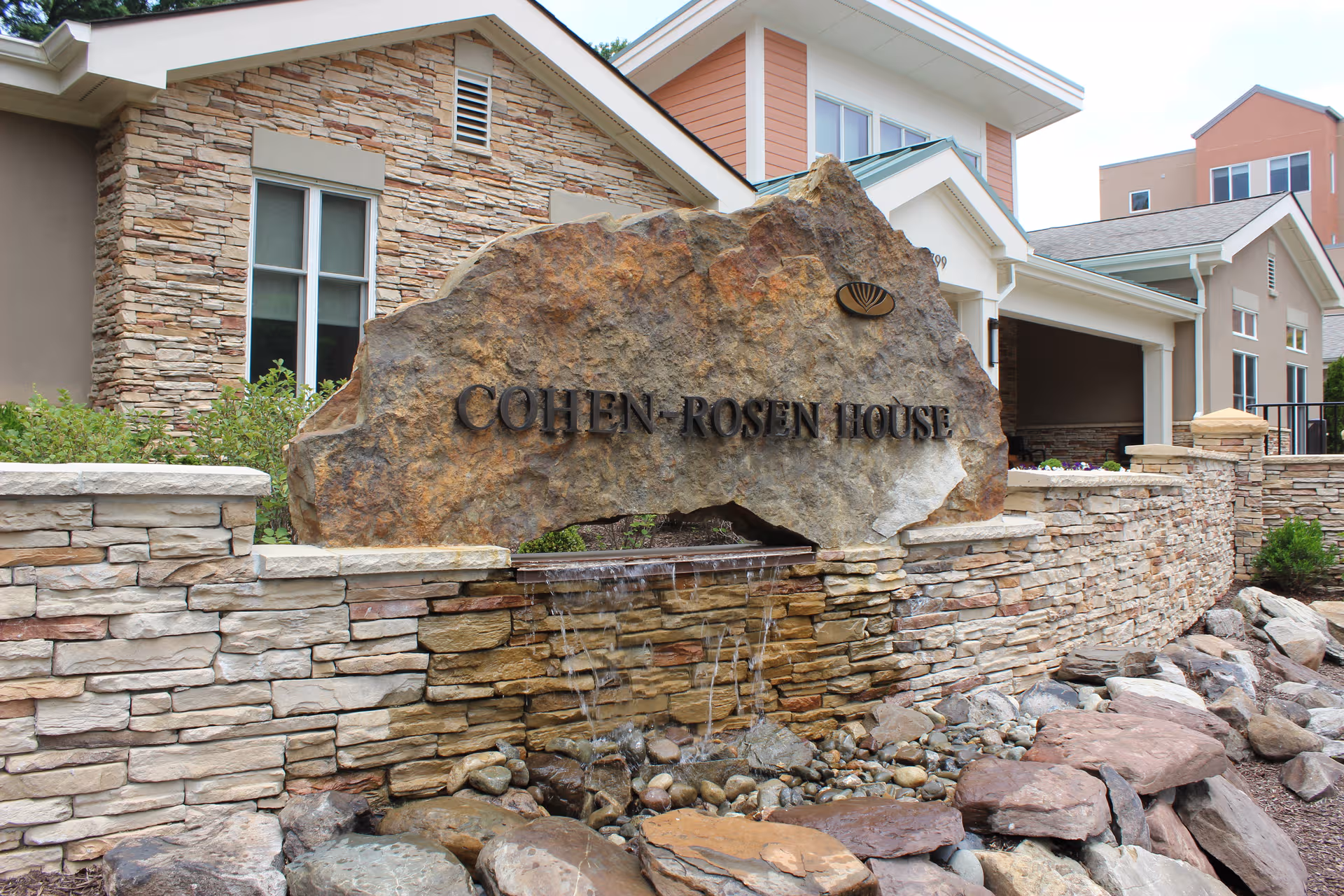 Stone sign engraved Cohen-Rosen House at the entrance of a senior living facility.