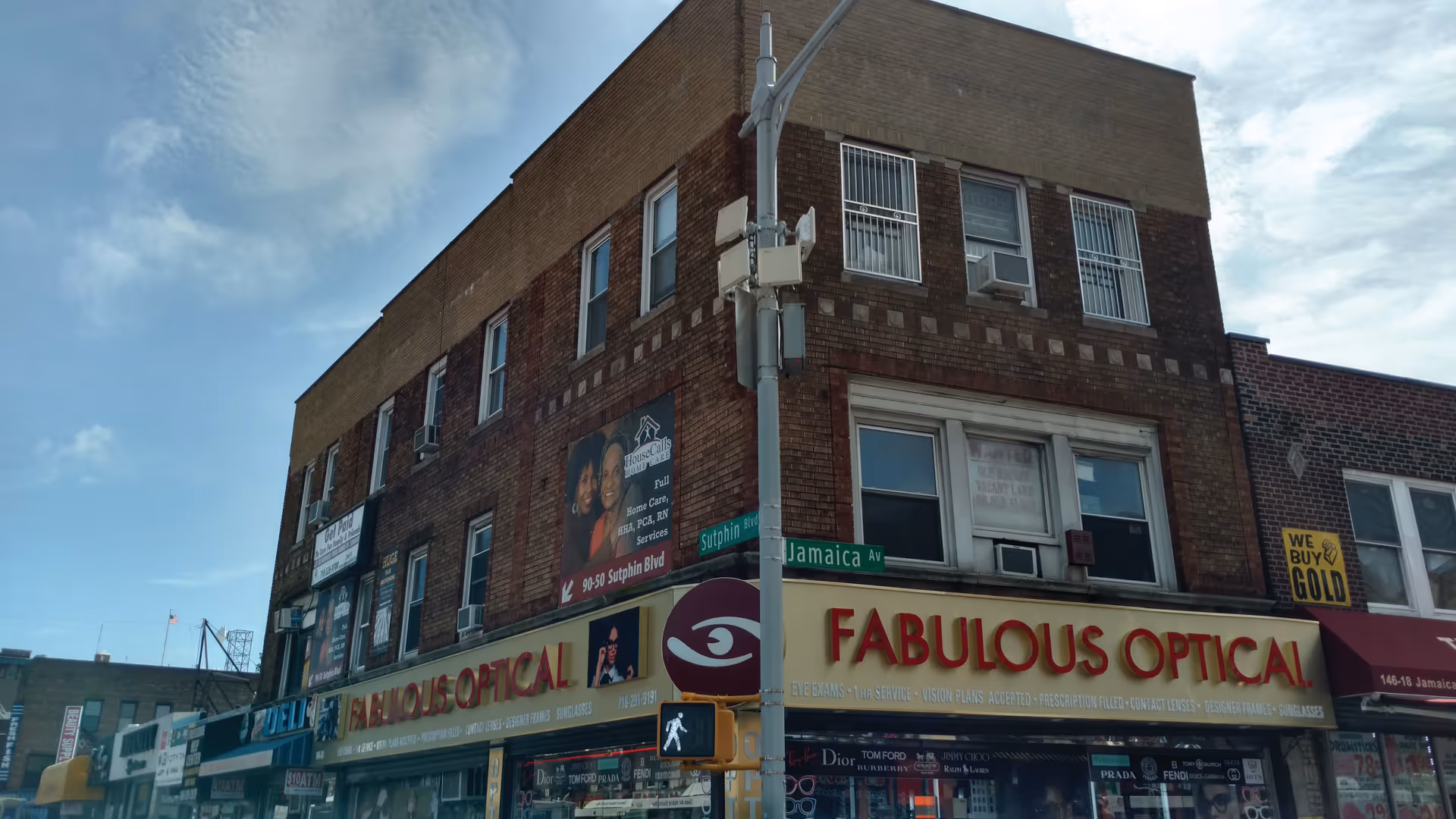 A brick storefront building with multiple signs, including a Fabulous Optical sign on the ground floor.