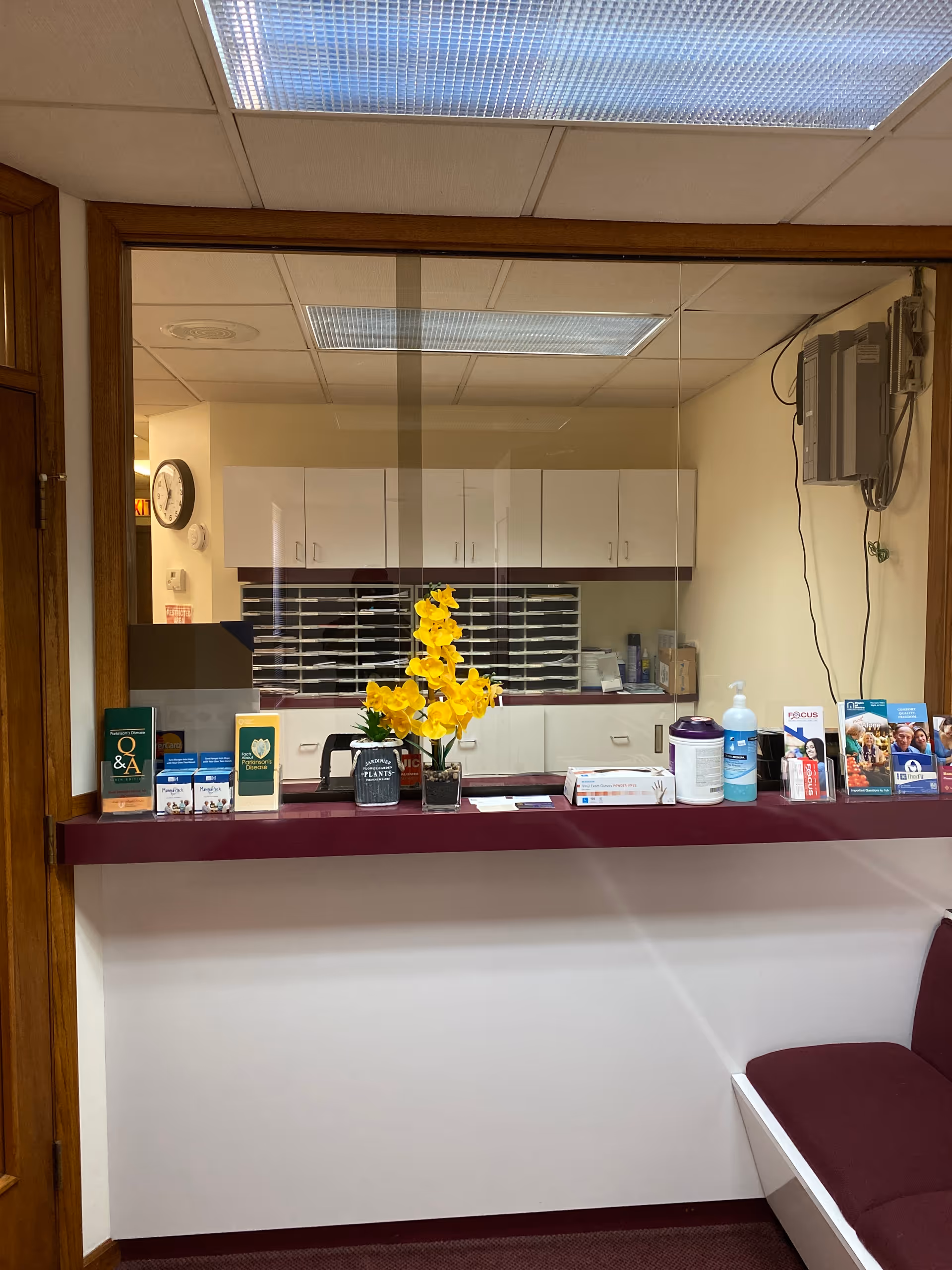 Reception window in a senior living facility showing a counter with flowers, brochures, and supplies.