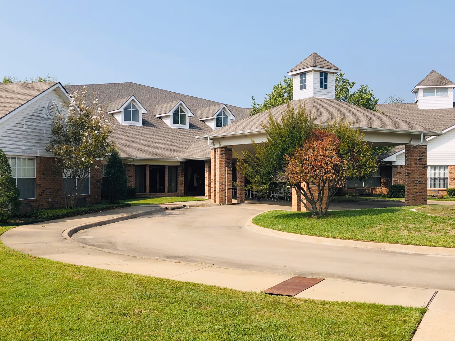 Exterior view of Crestwood Assisted Living showing a circular driveway and brick entrance.