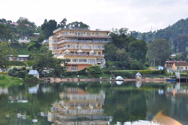 Lakeside multi-story building with balconies beside a calm, reflective lake.