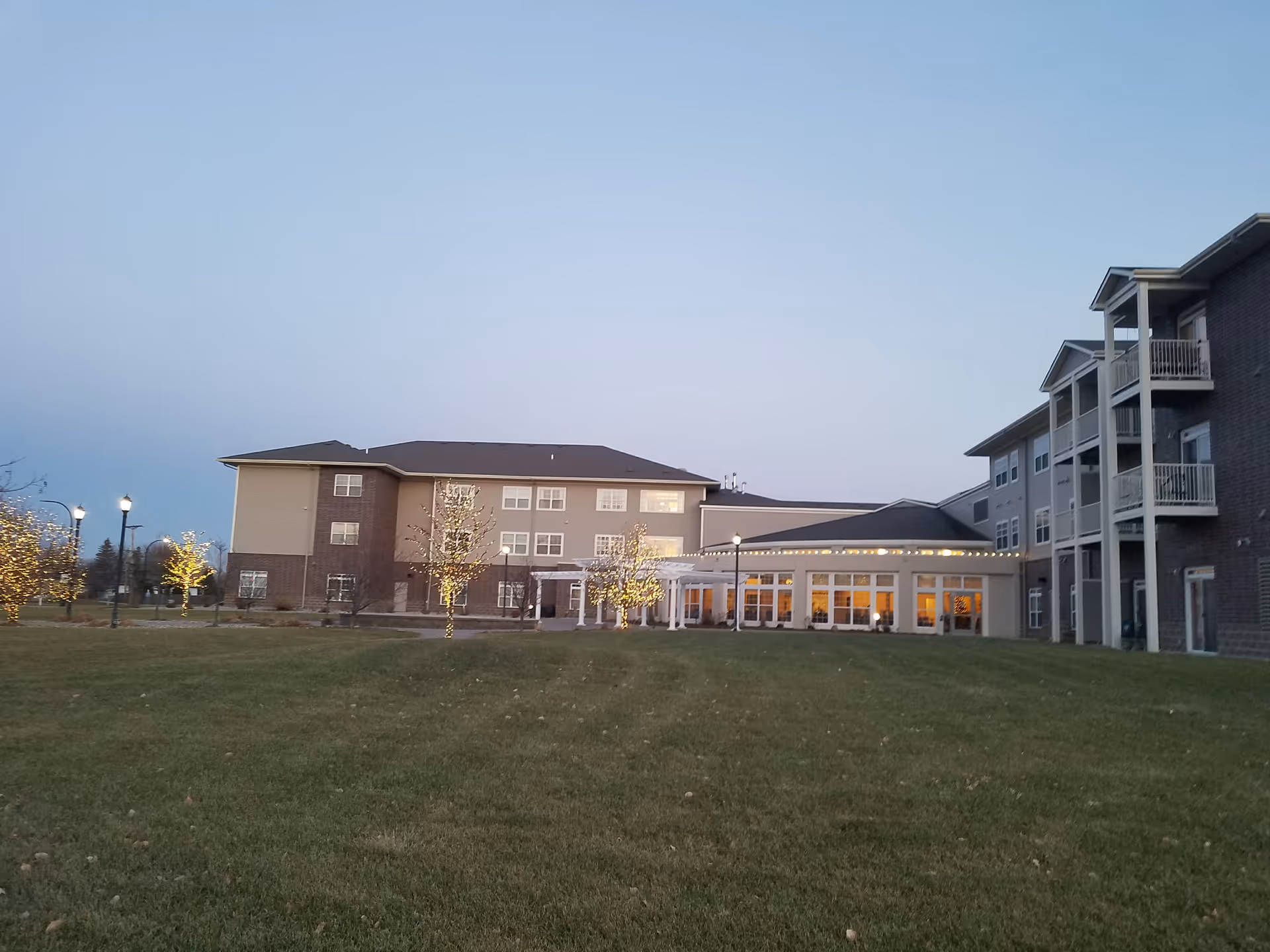 Exterior view of Eventide at Sheyenne Crossings, showing lit entrance and expansive lawn.