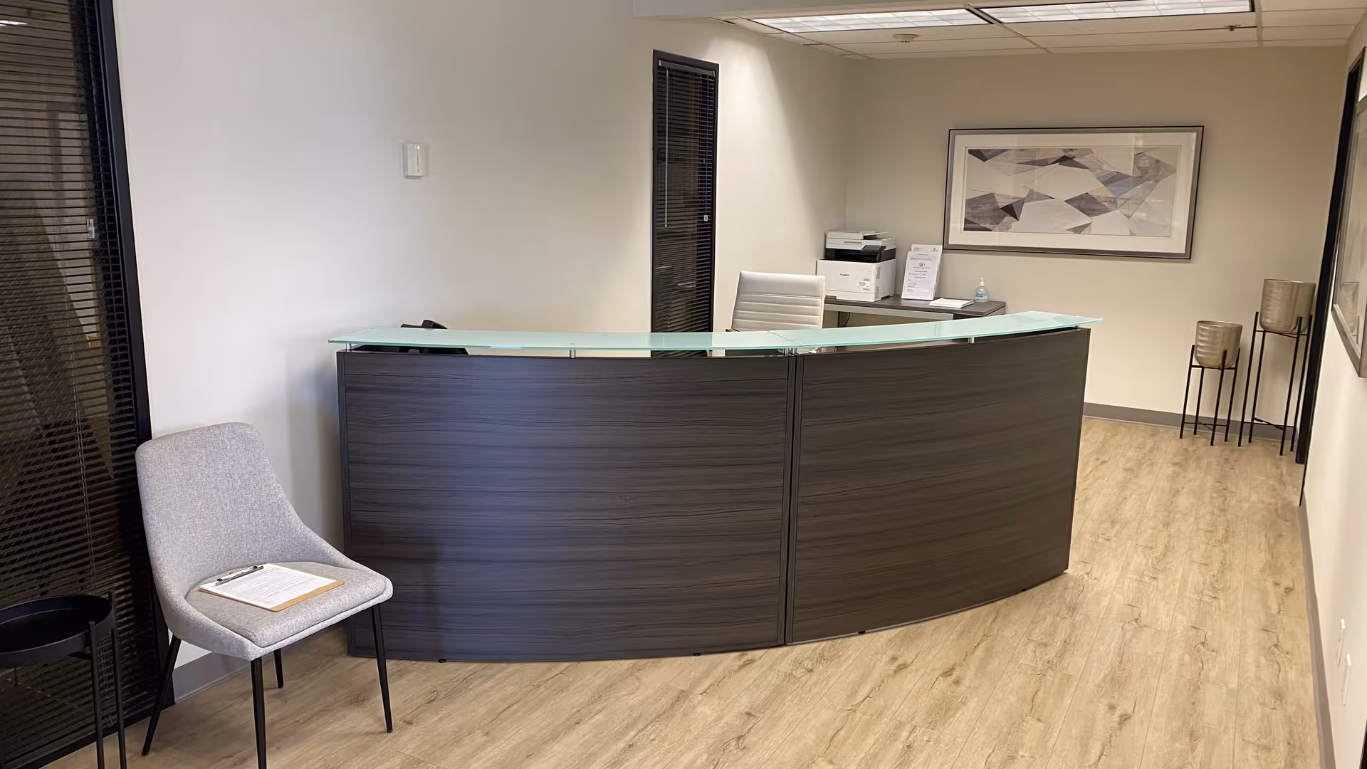 Curved reception desk in a modern lobby with chair and framed artwork.