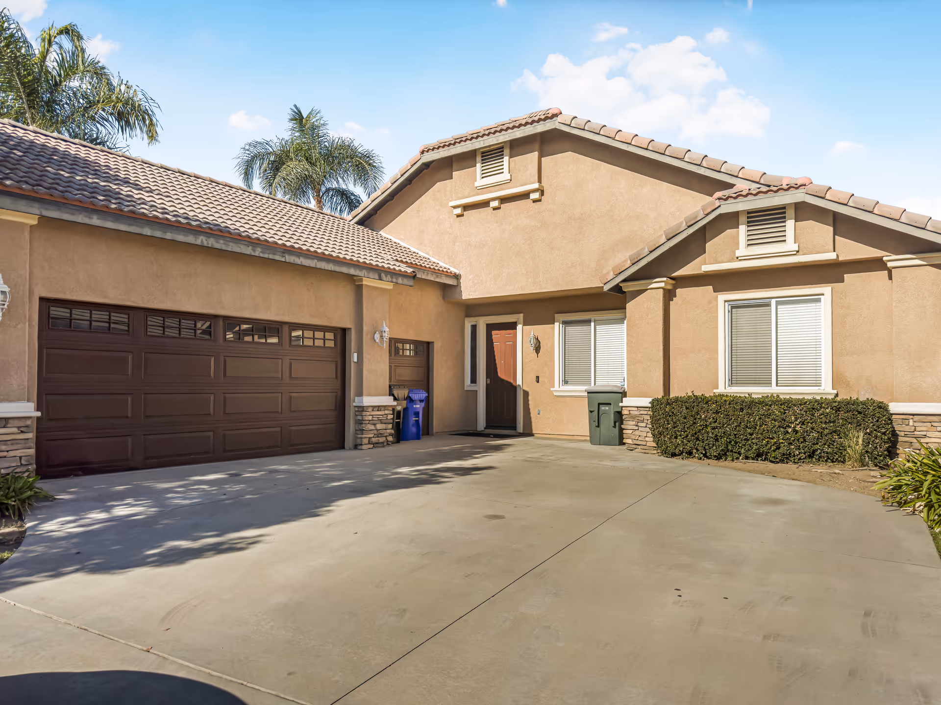 Front exterior of a tan care home with a two-car garage and driveway.