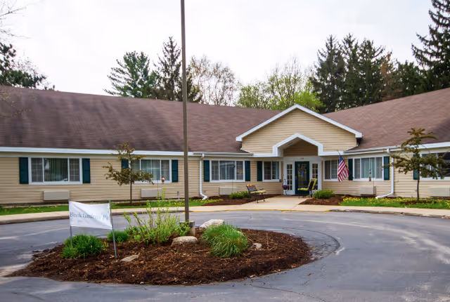 Exterior view of a single-story senior living facility with circular driveway and landscaped island.