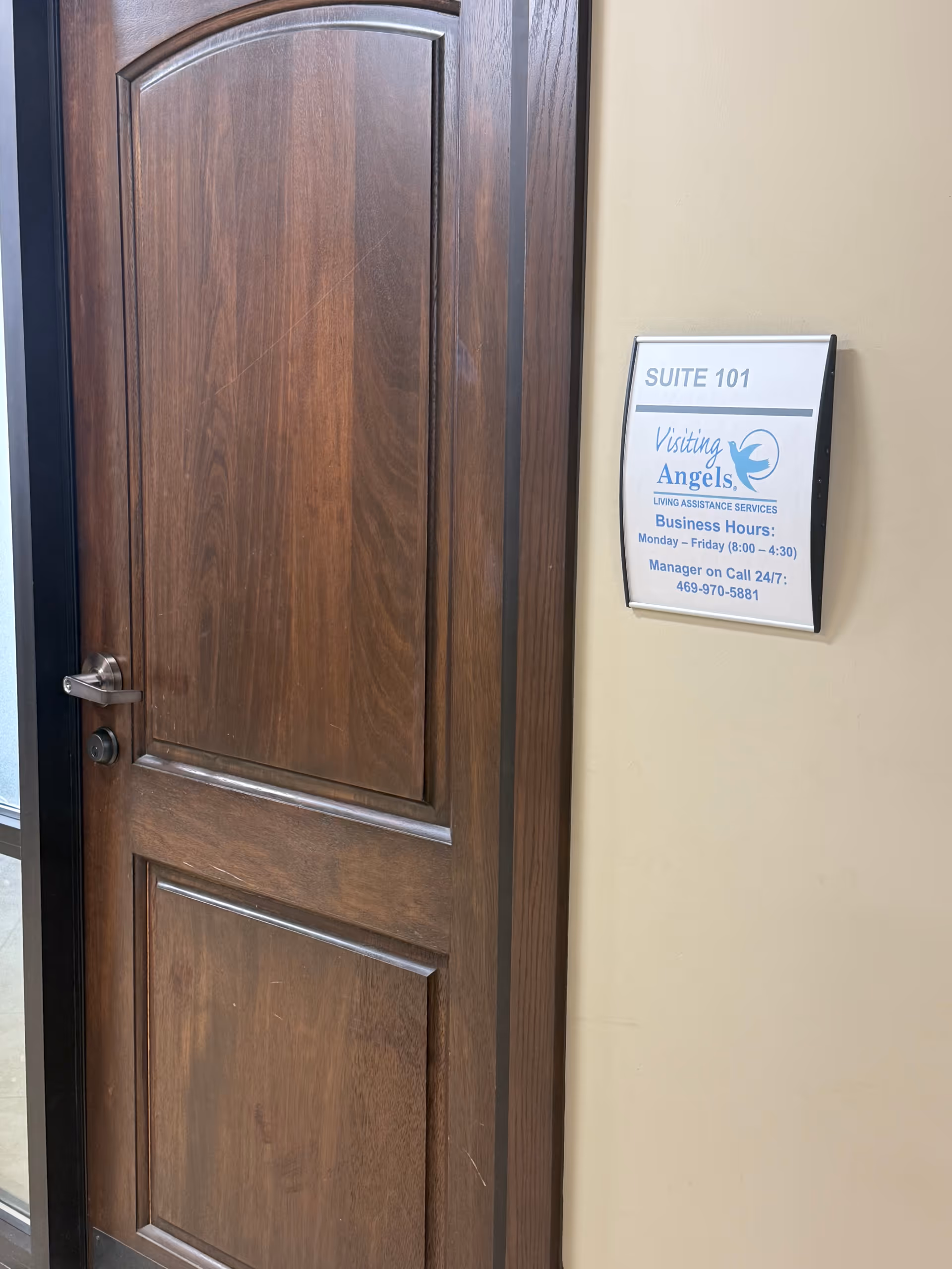 Wooden door beside wall sign for Visiting Angels Suite 101